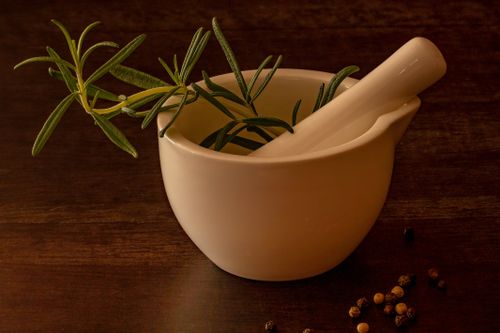 Free White porcelain mortar and pestle with rosemary on a wooden surface, ideal for culinary and herbal images. Stock Photo