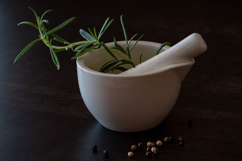 Free Elegant white porcelain mortar with fresh rosemary and peppercorns on a wooden surface. Stock Photo