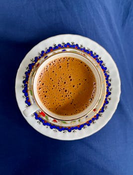 Traditional Turkish coffee served in a beautifully ornate cup on a blue cloth.