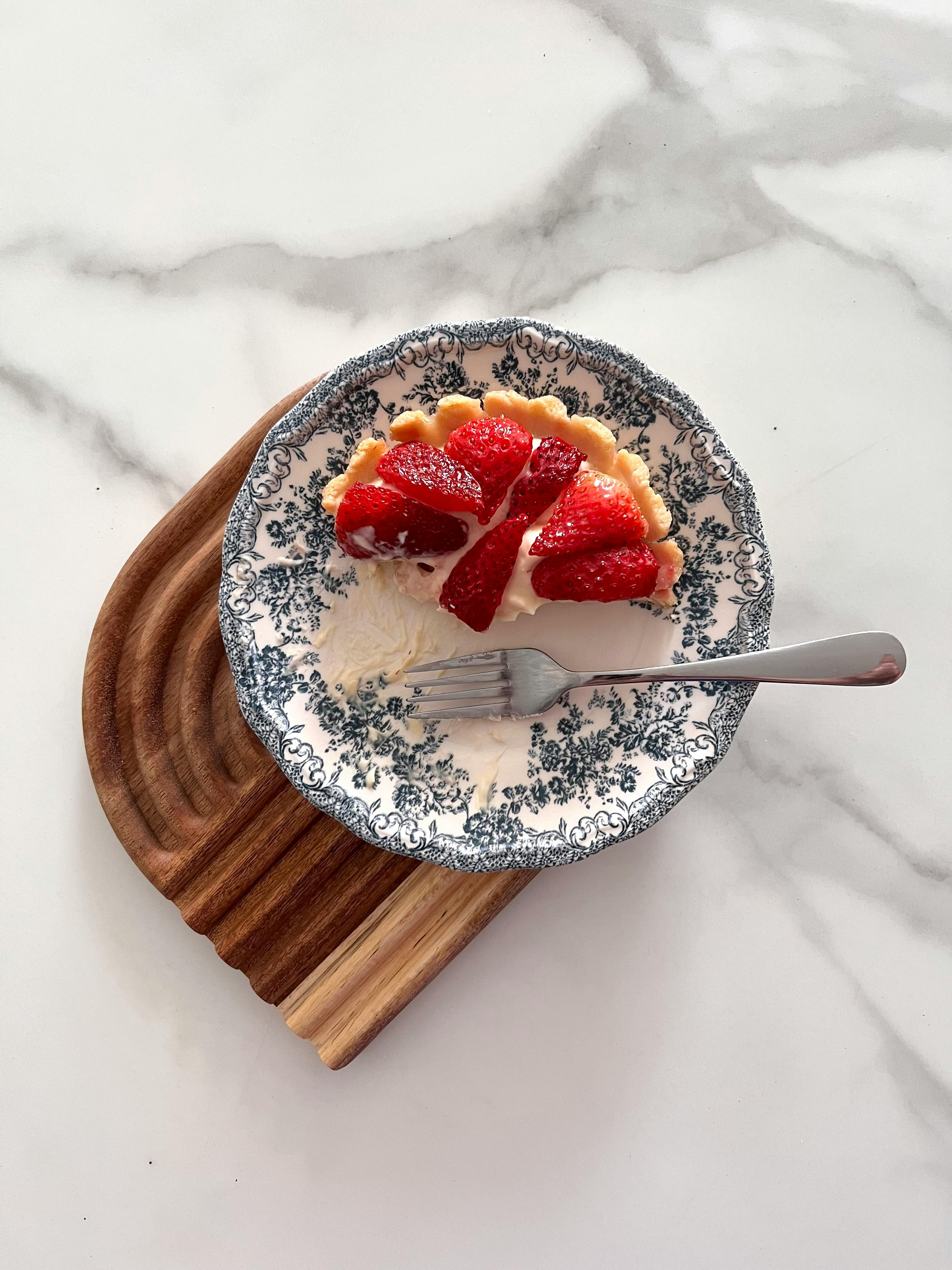 A mouthwatering strawberry tart on a decorative plate with a fork.