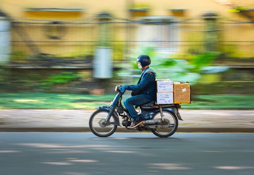 Side view of a motorcycle courier speeding down a road with packages in motion blur background.