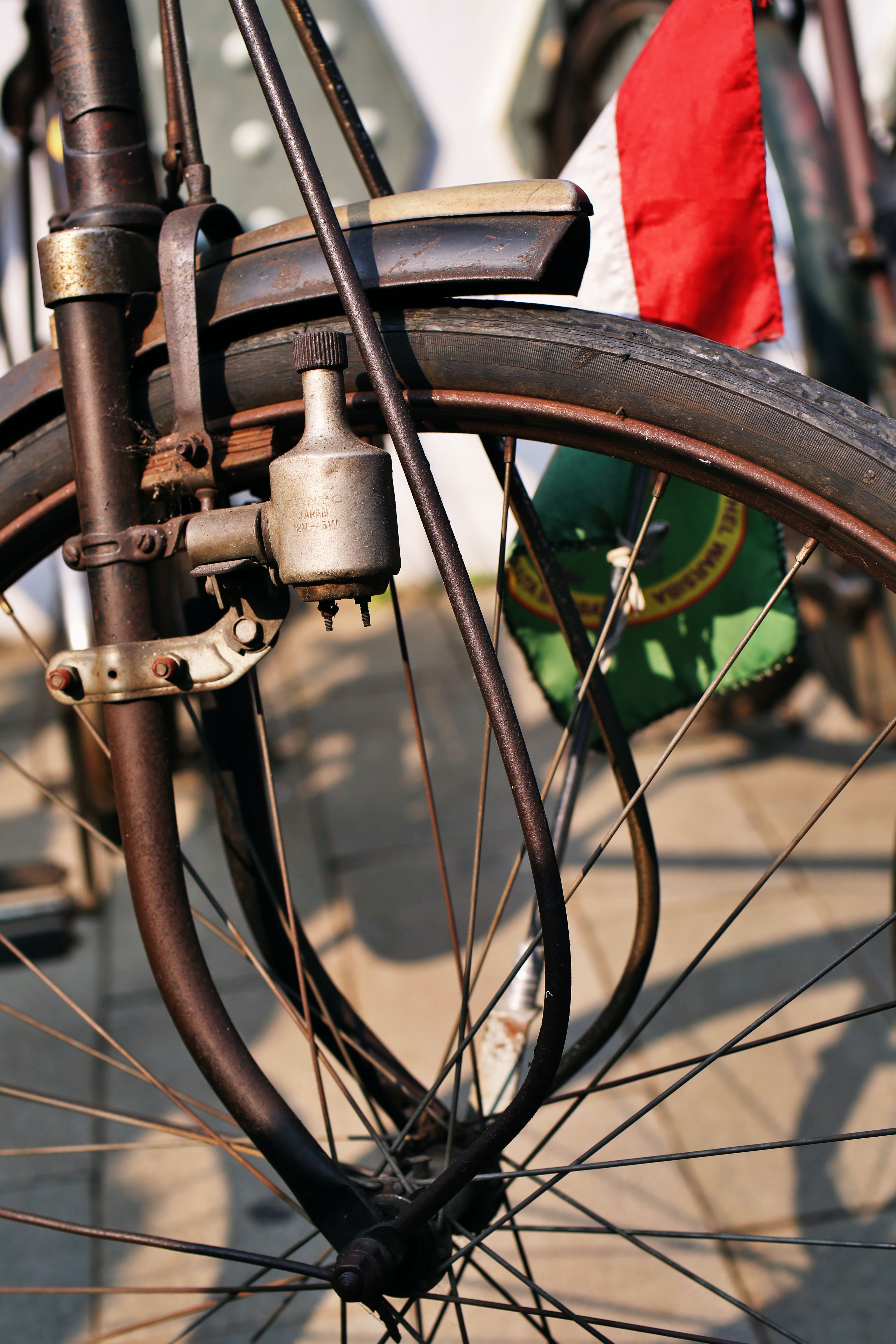 Close-up view of a vintage bicycle wheel with a tricolor flag attached, capturing a nostalgic feel.