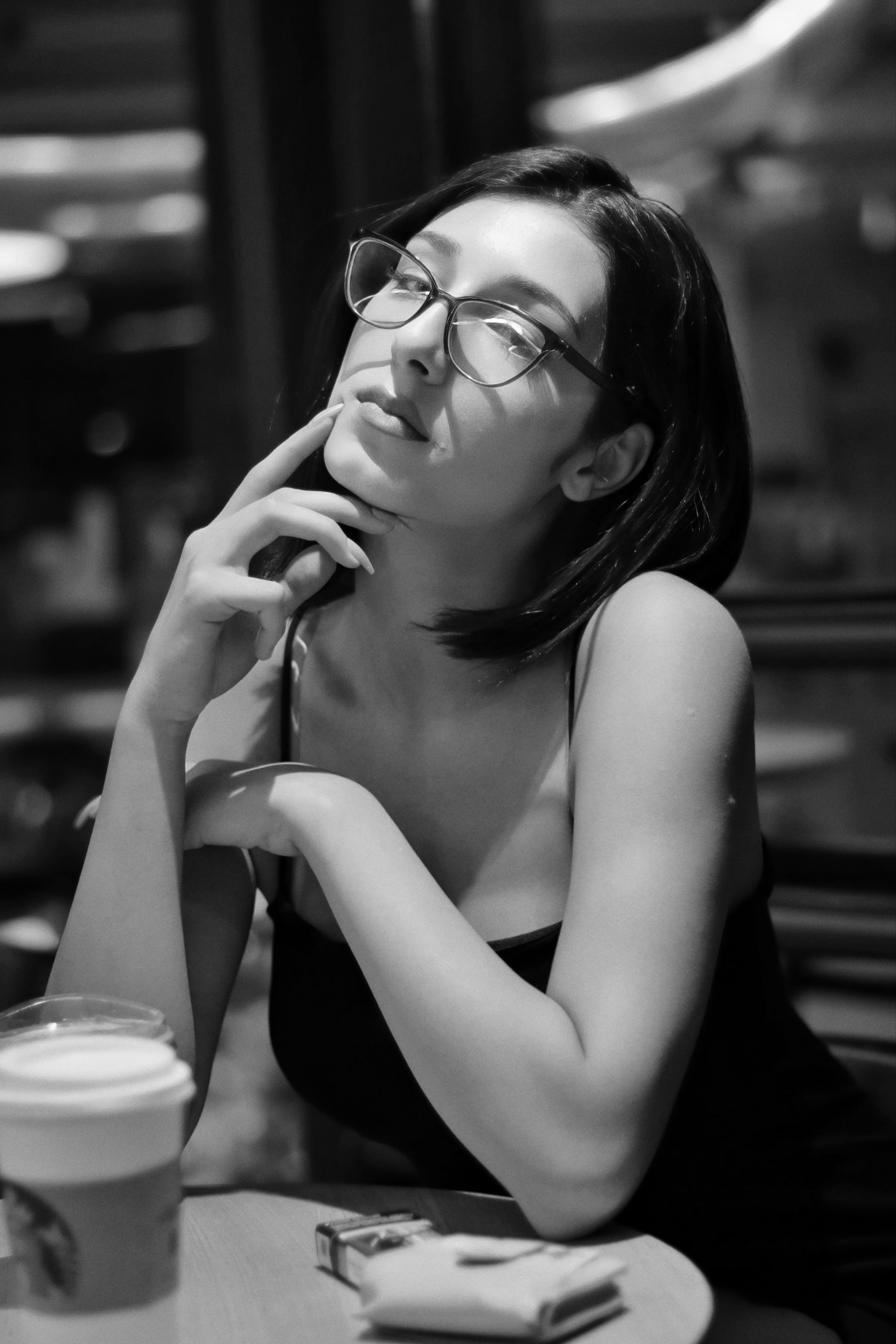 Black and white portrait of a woman in a cafe, deep in thought.
