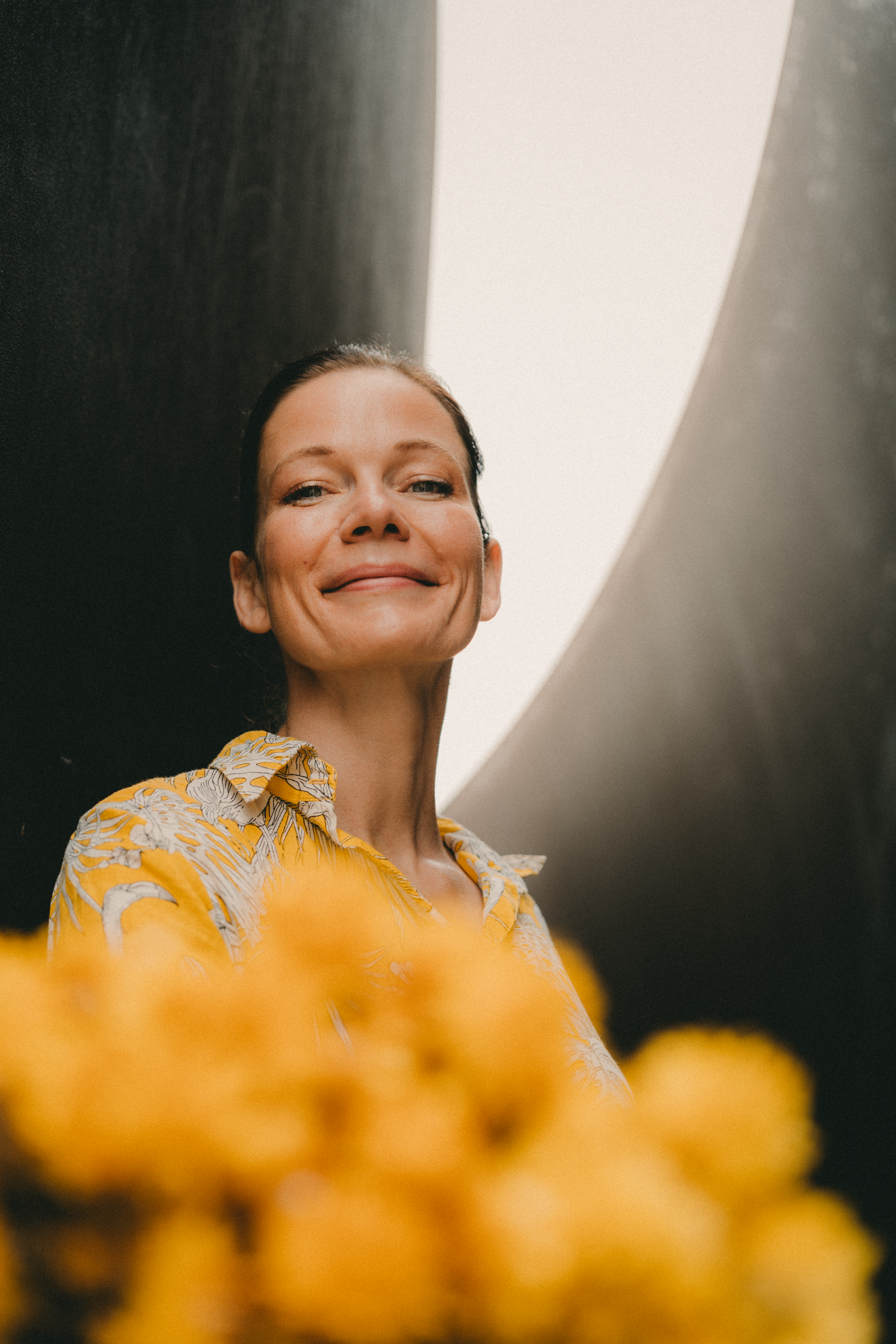 Artistic portrait of a smiling woman surrounded by vibrant yellow flowers, creating a joyful mood.