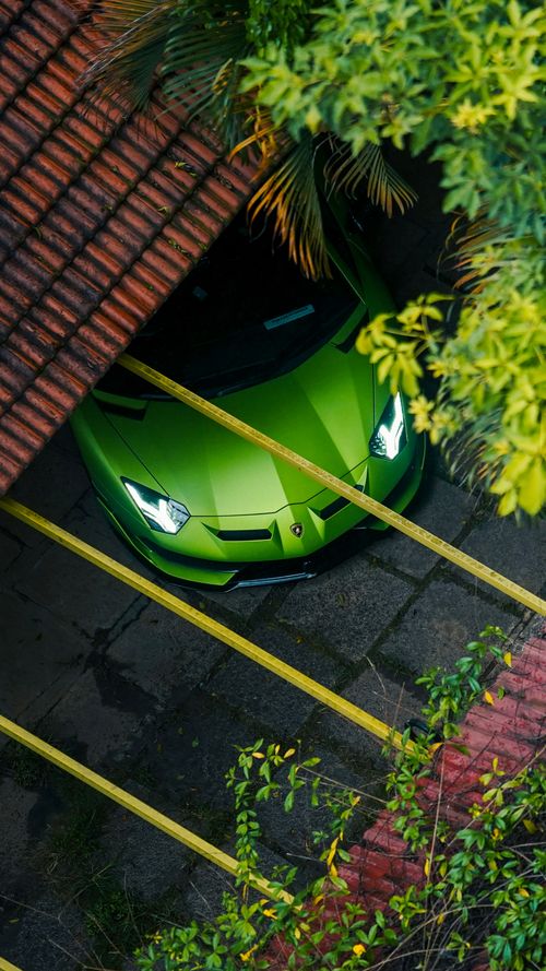 Free Stunning aerial view of a vibrant green supercar beneath a rustic roof surrounded by foliage. Stock Photo