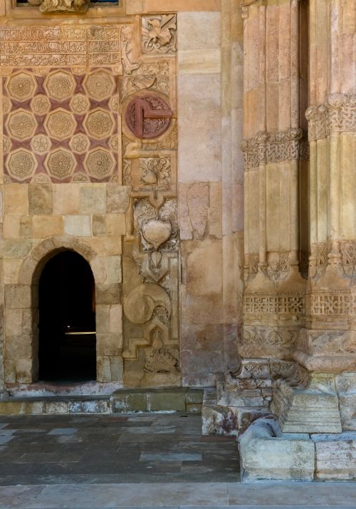 Free A detailed view of ancient stone architecture with intricate carvings and a small arched doorway. Stock Photo