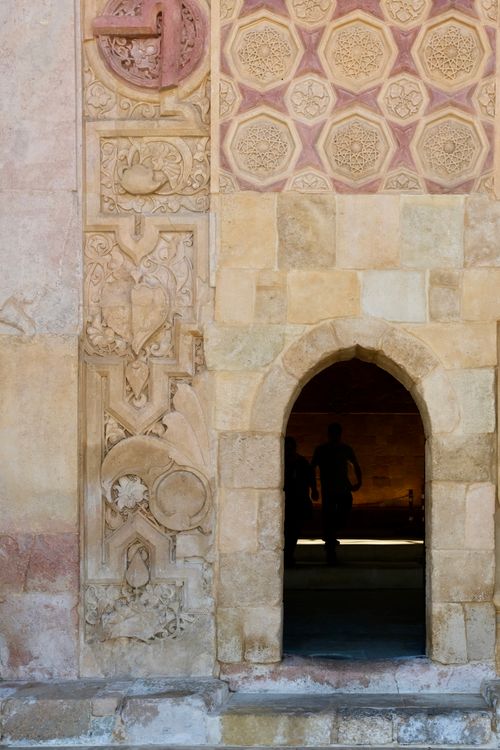 Free A silhouette visible through an ornate archway with detailed stone carvings and patterned walls. Stock Photo