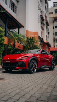 Elegant red sports car parked in a cityscape setting, showcasing modern architecture and design.