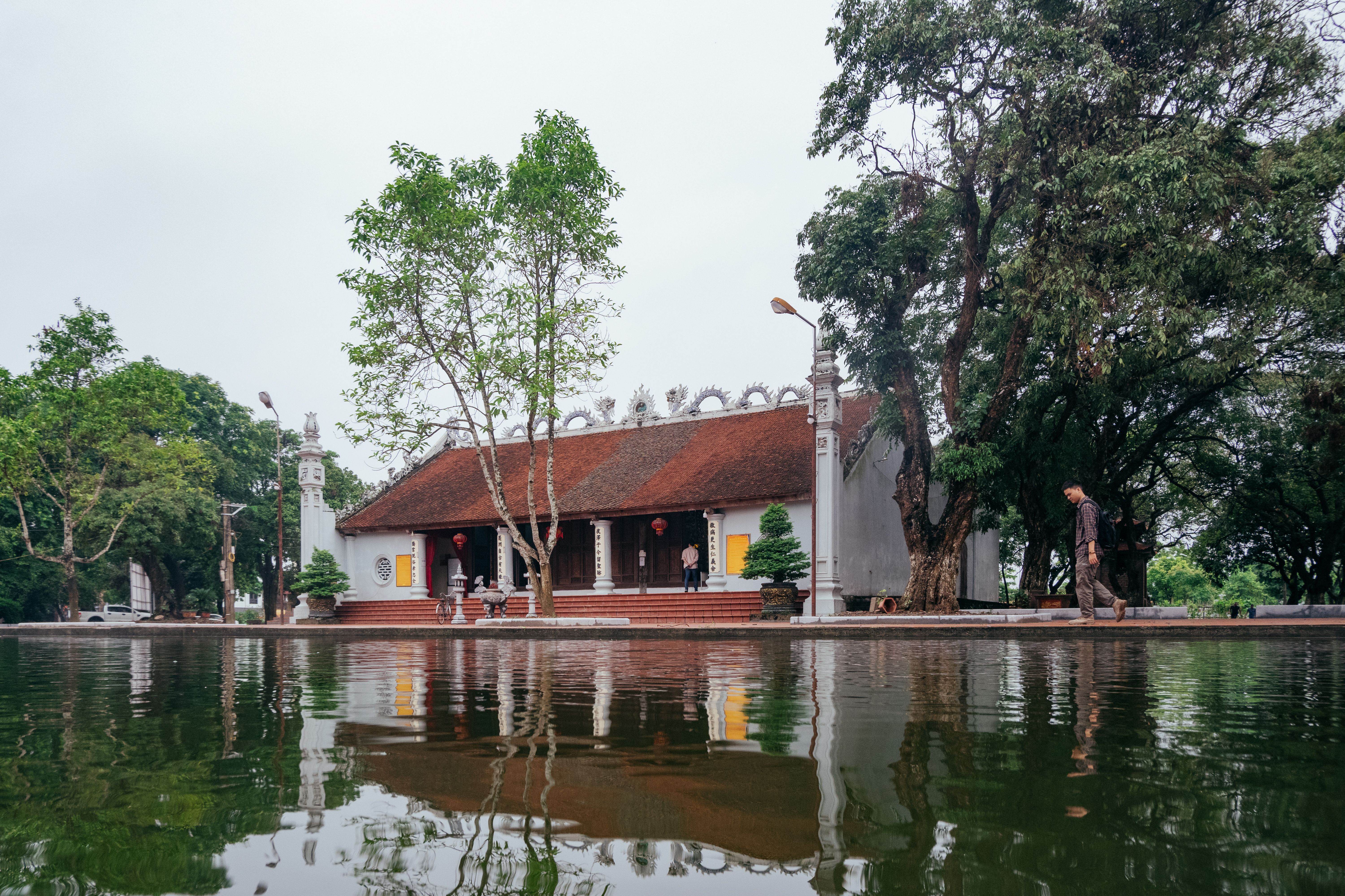Serene view of a traditional Vietnamese temple by a reflective pond in Hưng Yên, Vietnam.