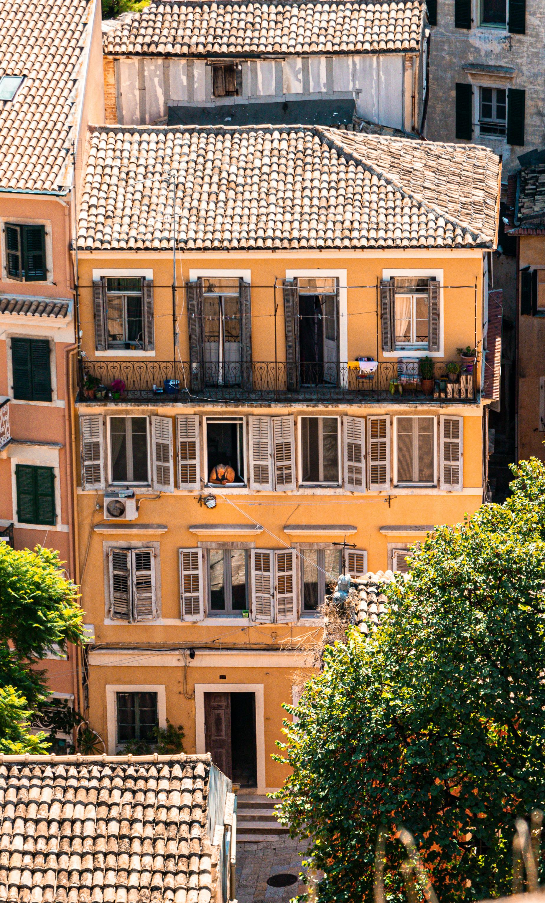 Charming view of a sunlit building facade in Corfu, Greece, highlighting the Mediterranean style.
