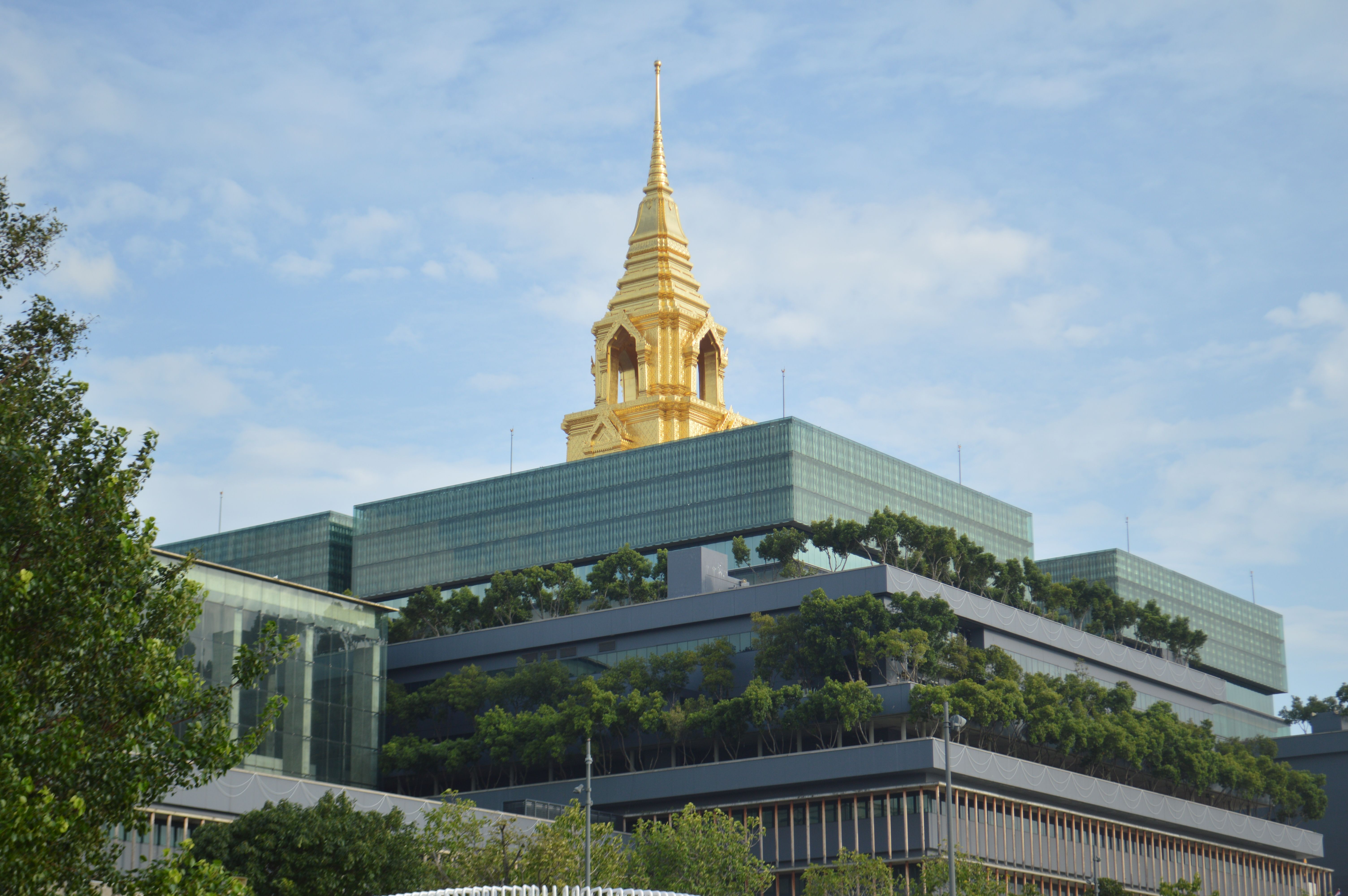 Eco-friendly modern architecture with golden spire against a clear sky in a cityscape setting.
