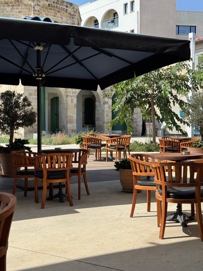 Empty outdoor patio with wooden chairs under umbrellas — photo by Niki on Pexels