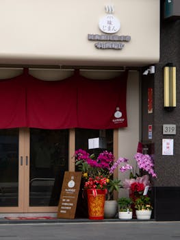 Flower-adorned entrance of a local shop in Miaoli, Taiwan, featuring red curtains.
