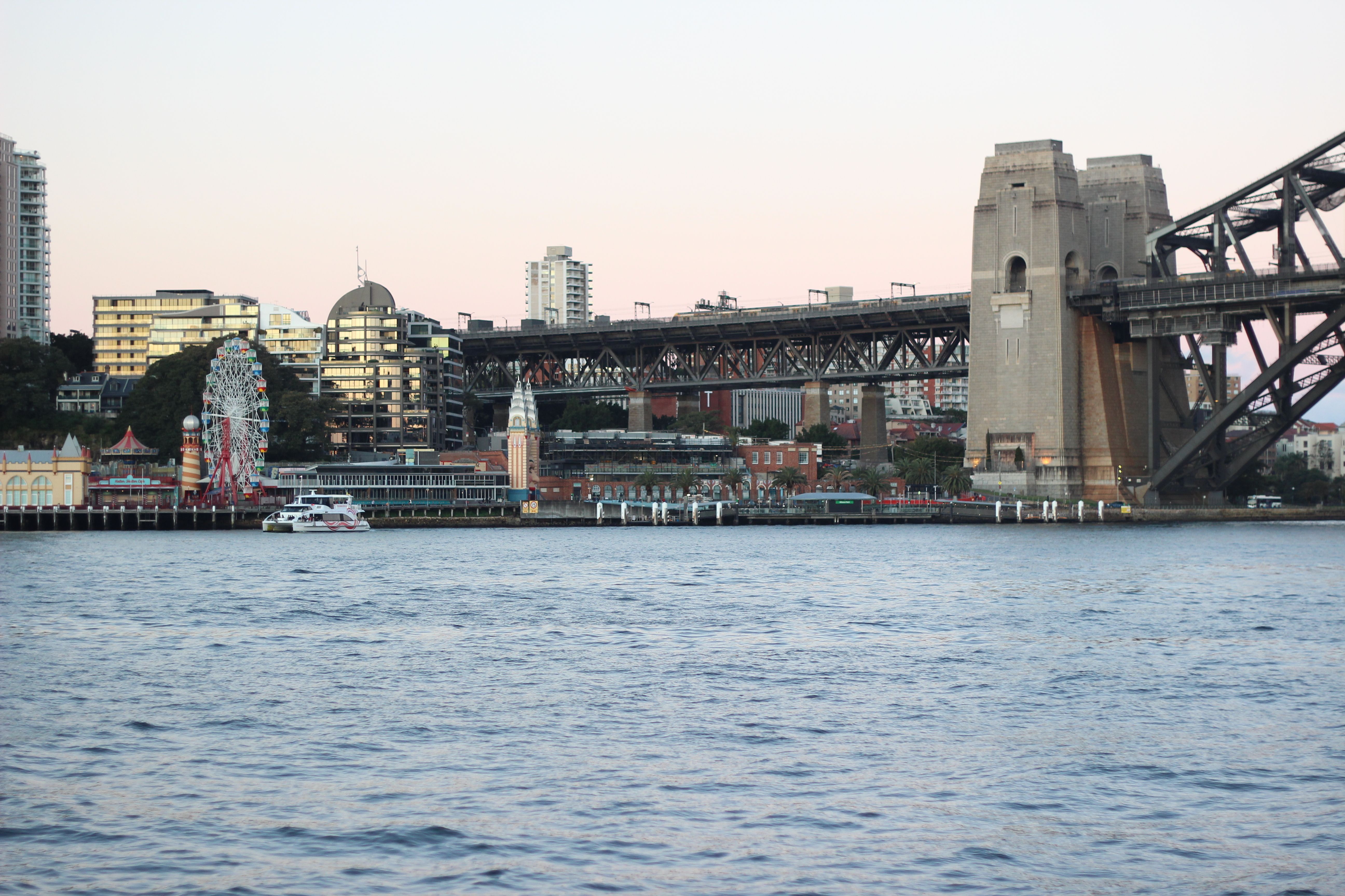 Dusk view of Sydney Harbour Bridge and Luna Park from the water.