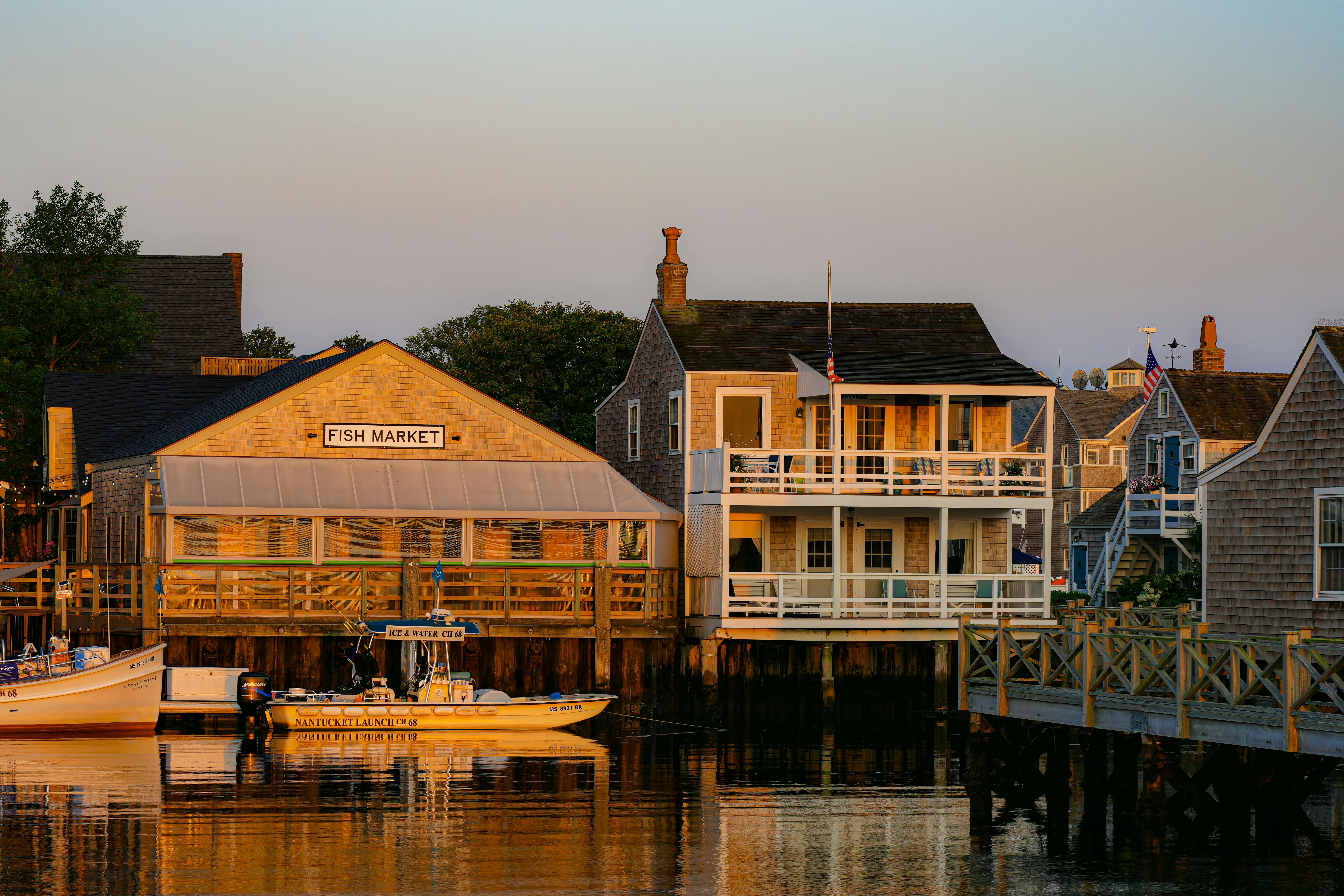 Beautiful view of Nantucket harbor with boats and charming coastal buildings at sunset.