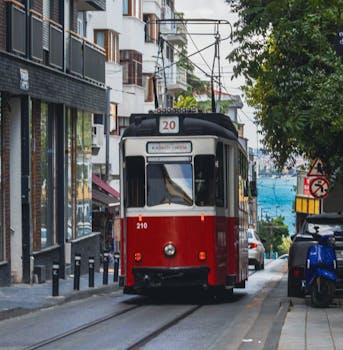 Classic red tram traveling through a vibrant Istanbul street, rich in local architecture.