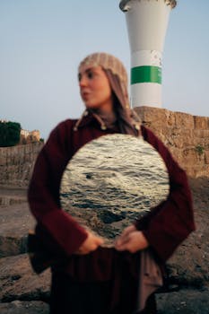 A unique portrait of a woman outdoors with a mirror reflecting the ocean.