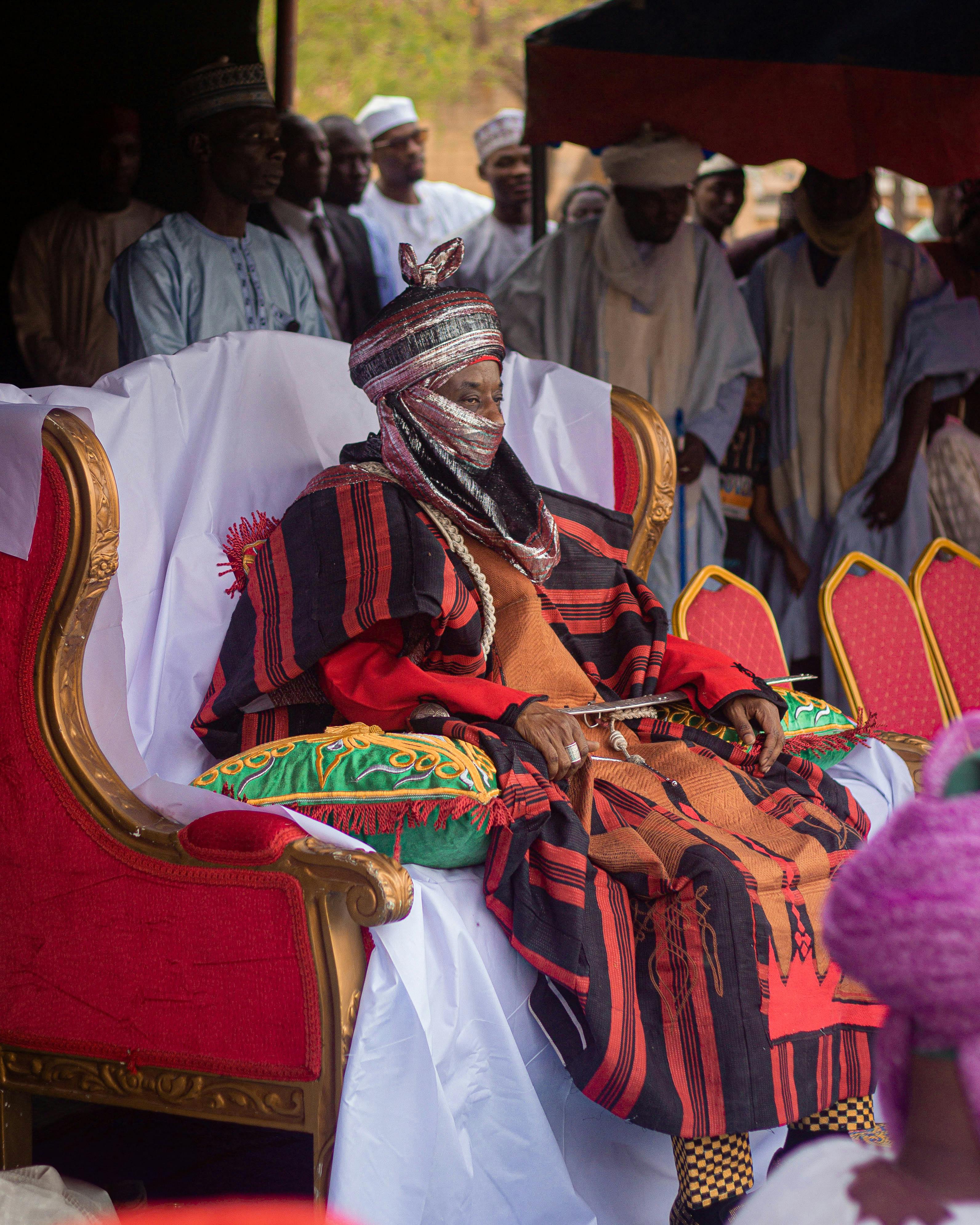 Cultural ceremony featuring a person in traditional African attire seated on a throne.