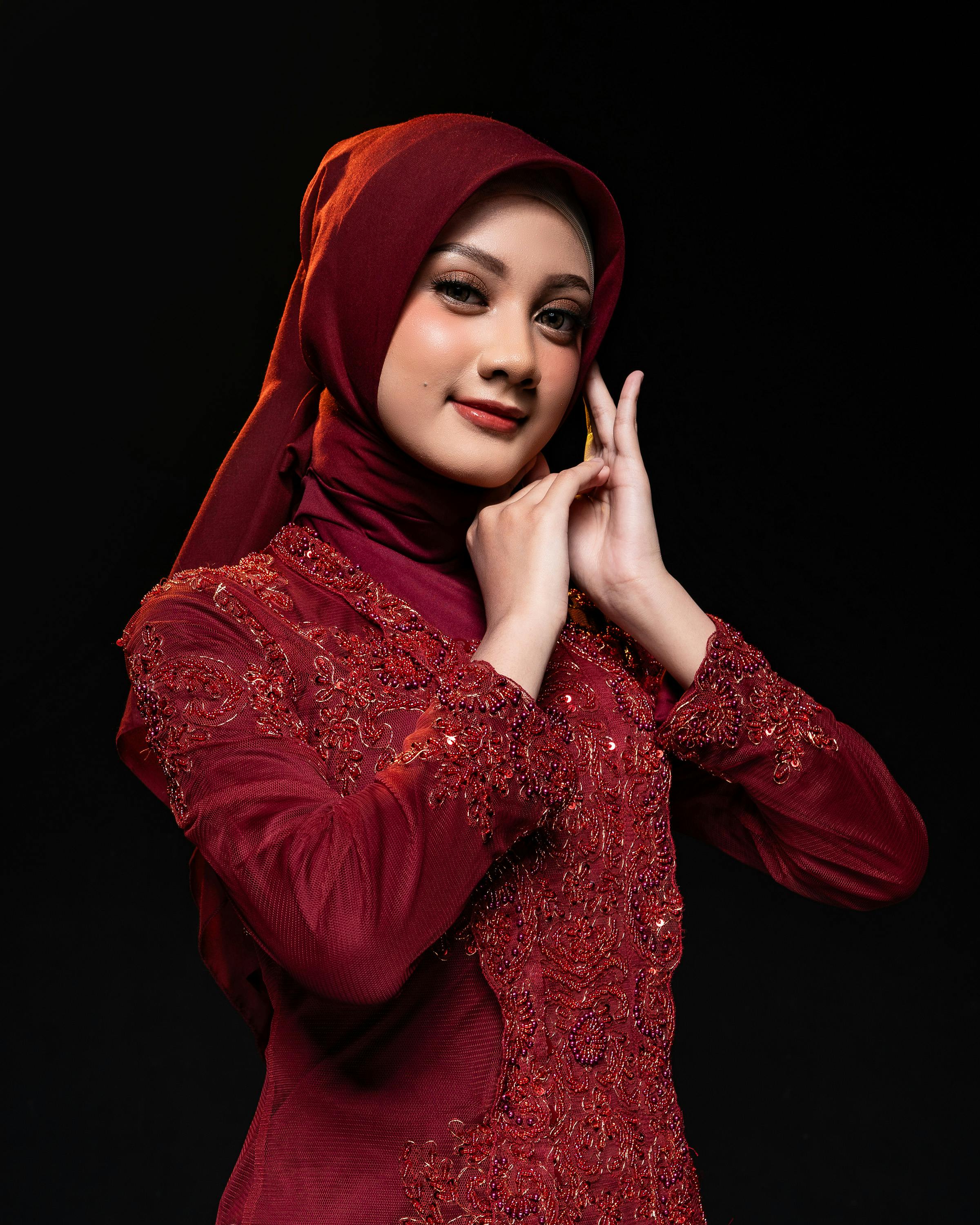 Portrait of a woman wearing a red hijab and ornate traditional dress, embodying grace.