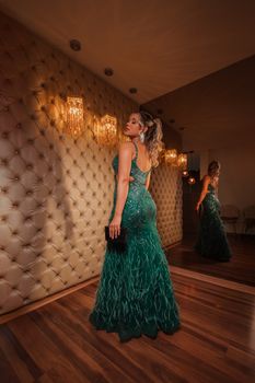 Sophisticated woman in green evening dress poses in luxurious indoor setting, highlighting fashion and elegance.