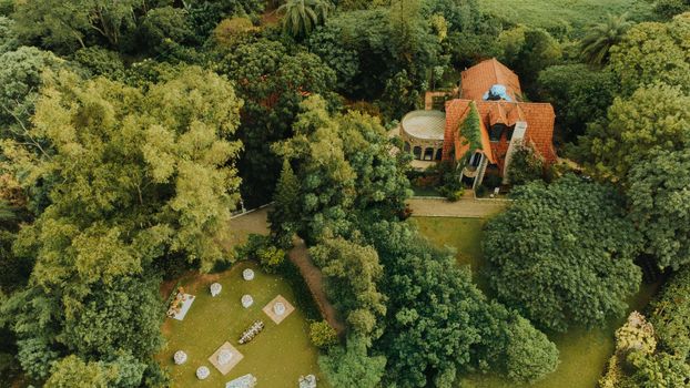 Aerial shot of a charming manor surrounded by lush greenery and a beautifully landscaped garden.