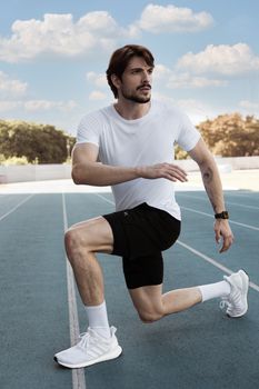 Focused young athlete on outdoor track ready to sprint, showcasing fitness and determination.