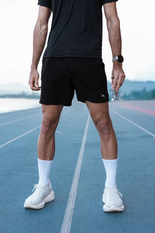 Free Athlete in sportswear standing on a running track with water bottle, ready for workout Stock Photo