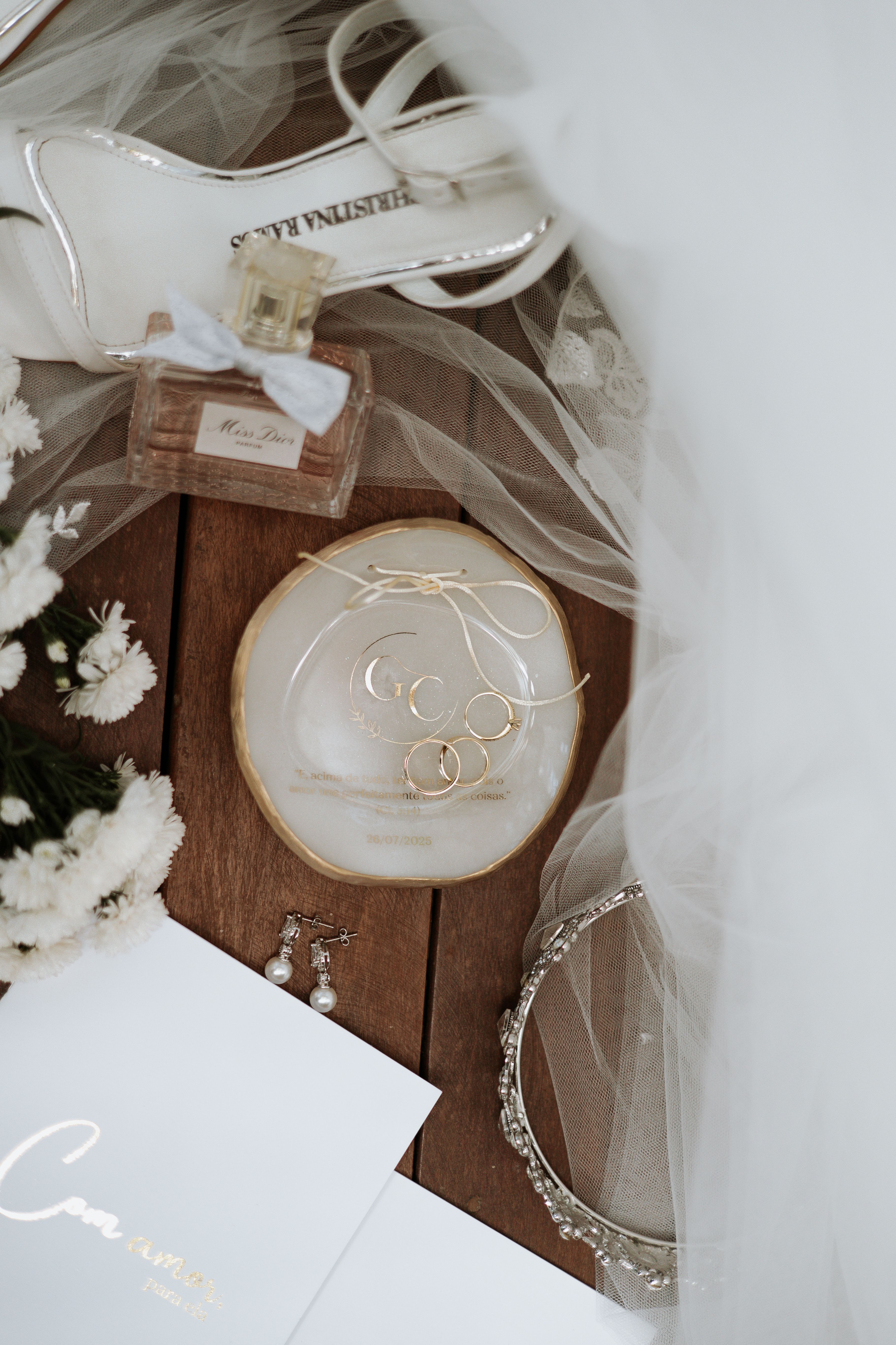 Flat lay of bridal accessories including jewelry, perfume, and flowers.