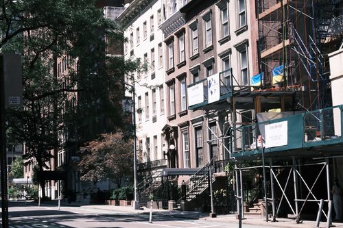 Free A sunny street with historic buildings and renovation scaffolding, capturing urban life. Stock Photo