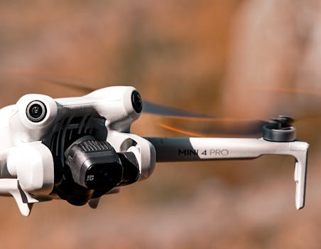 A close-up of a drone mid-flight, showcasing its camera and sleek design against a blurred background.
