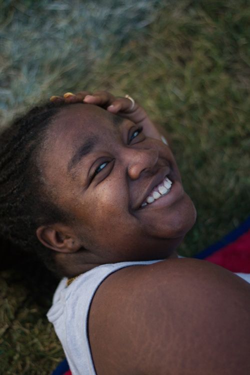 Free Portrait of a joyful woman lying on grass, enjoying a relaxing day outdoors. Stock Photo