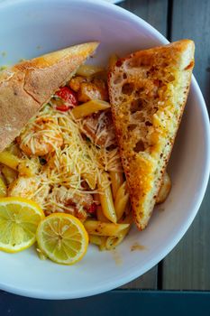 Delicious gourmet pasta with garlic bread and lemon slices served in a Denver restaurant.