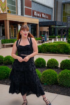Stylish woman in a black dress posing outside Kona Grill in Denver, Colorado.