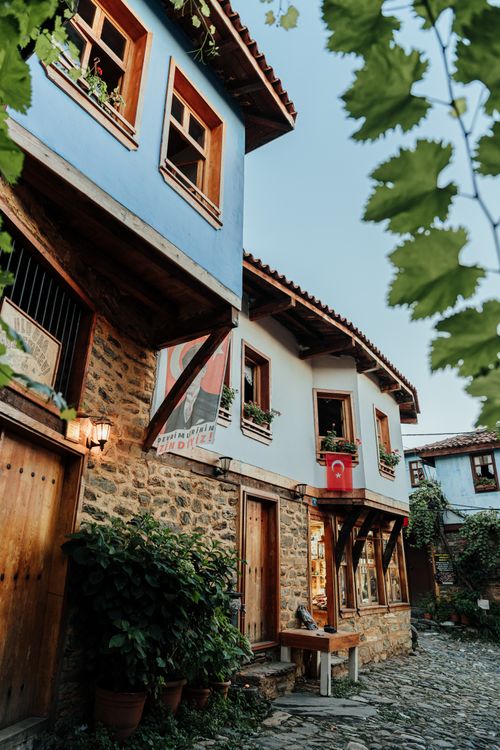 Free Historic Ottoman architecture in the quaint village street of Cumalıkızık, adorned with flags and greenery. Stock Photo