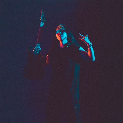 Free A cool musician poses with an electric guitar under vibrant lighting, capturing the essence of rock. Stock Photo