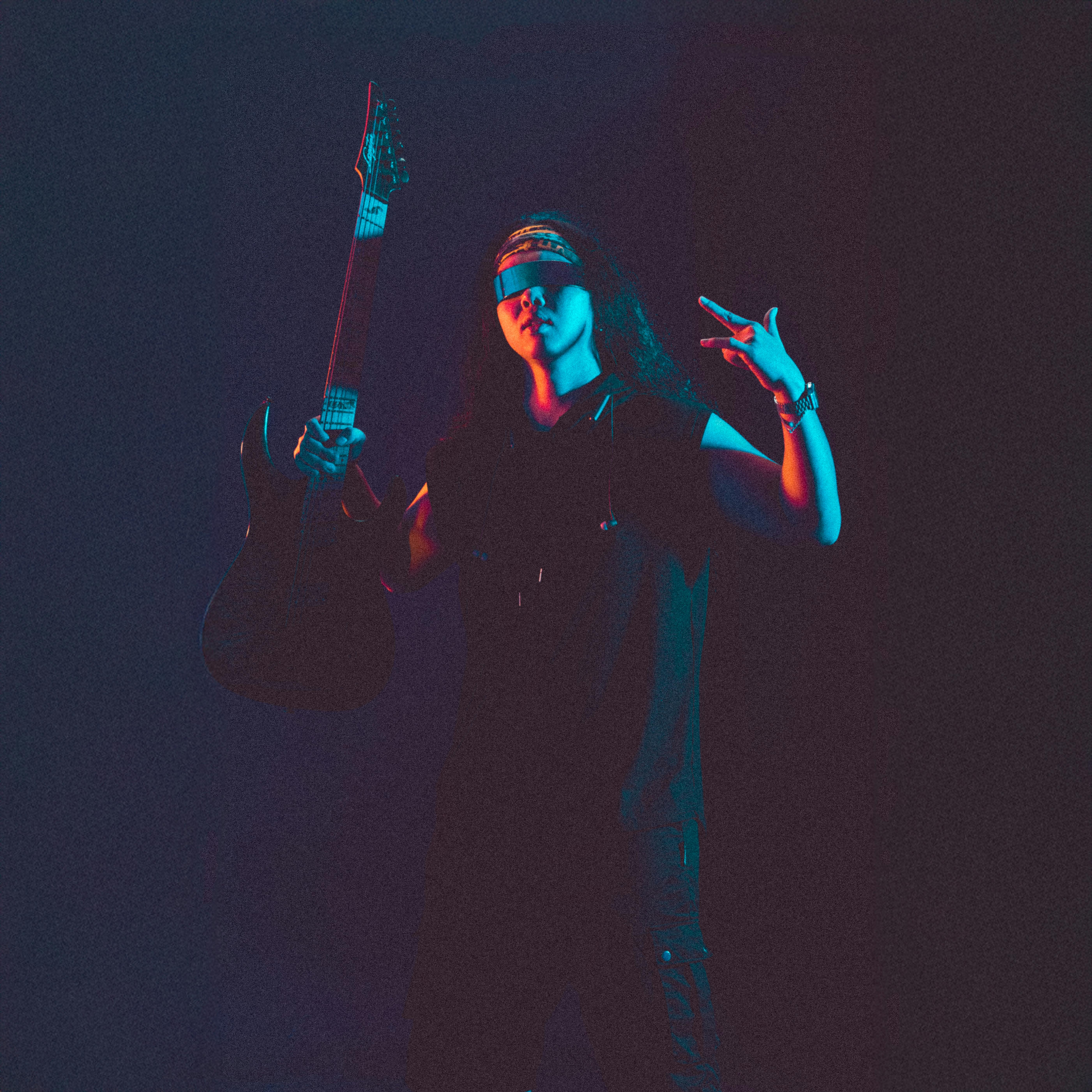 bezplatná Skvělý hudebník pózuje s elektrickou kytarou pod zářivým osvětlením a zachycuje tak podstatu rocku. Základová fotografie