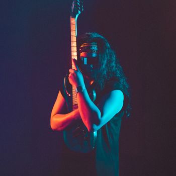 Dramatic neon-lit portrait of a guitarist in Hà Nội showcasing rock style and attitude.