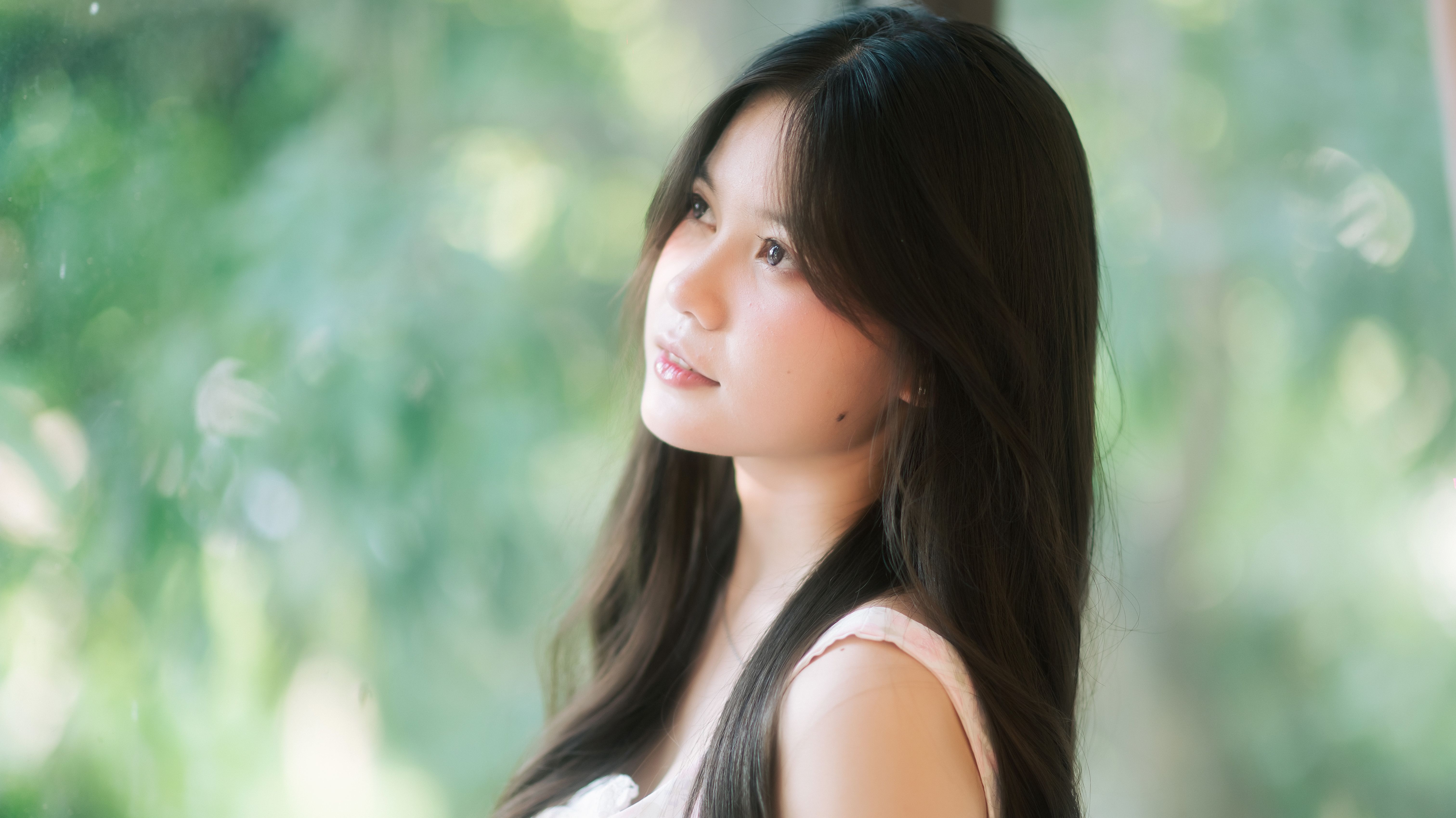 A serene portrait of a young woman looking outdoors, bathed in natural light.