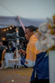 Event photographer with gimbal capturing dynamic footage outdoors during day.