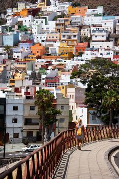 Vibrant hillside architecture with a pedestrian in Tenerife, Spain on a sunny day.