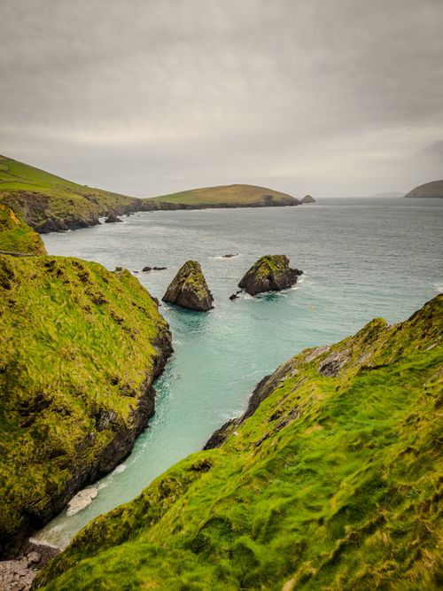 Free Breathtaking cliffs and sea stacks in Dunquin, Ireland, with lush greenery and the wild Atlantic Ocean. Stock Photo
