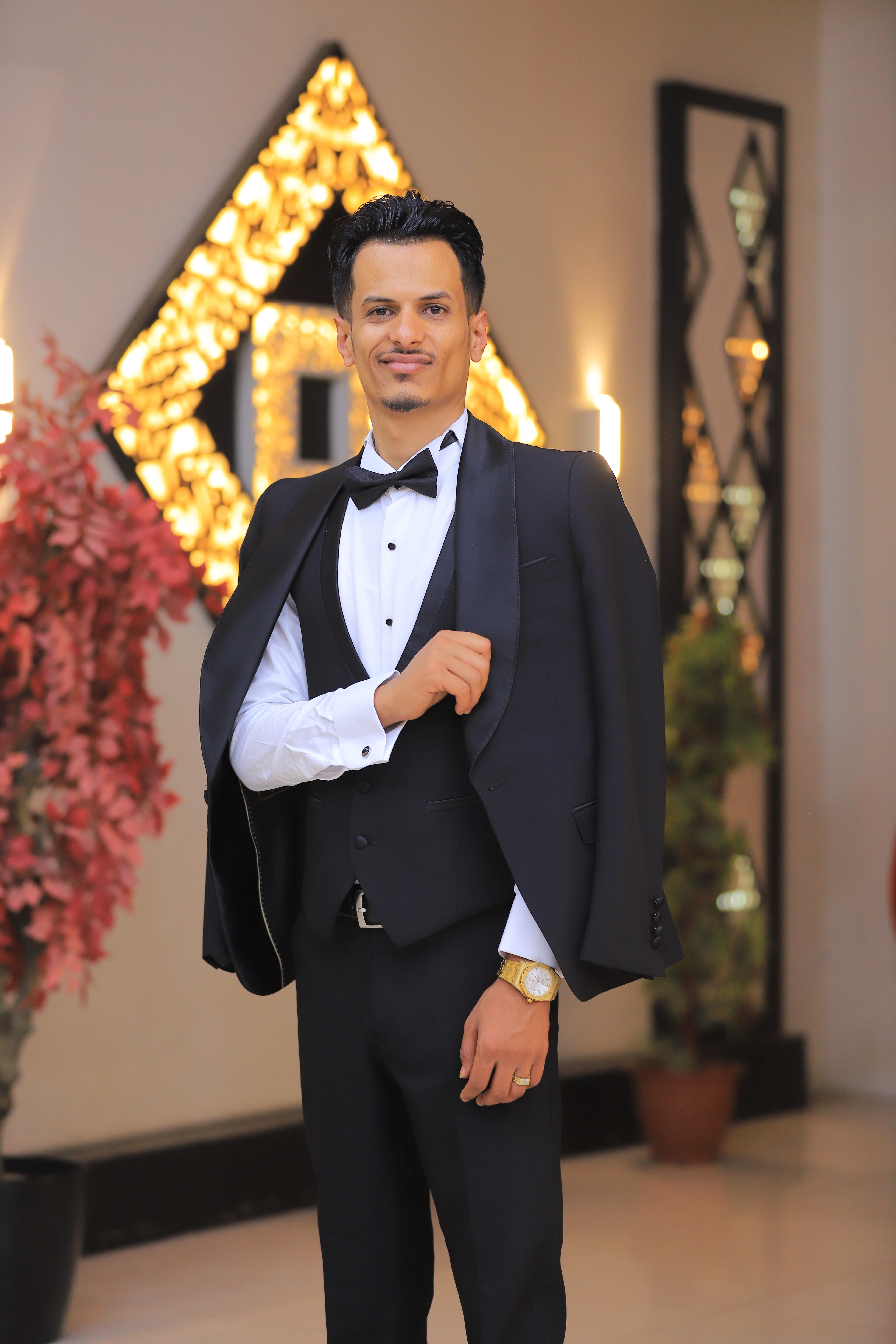 Man in tuxedo posing at a formal indoor event, exuding elegance and sophistication.