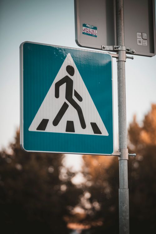 Free Pedestrian crossing sign with trees in the background, day setting. Stock Photo