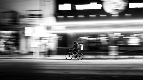 Free Black and white photo of a cyclist in motion blur, capturing urban night life in Bahía Blanca, Argentina. Stock Photo