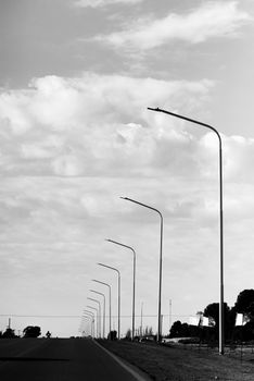 Black and white photo of a road with streetlights in Bahía Blanca, Argentina.