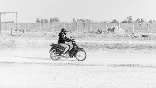 Free A motorcyclist rides on a dusty road in Bahía Blanca, capturing urban life in black and white. Stock Photo