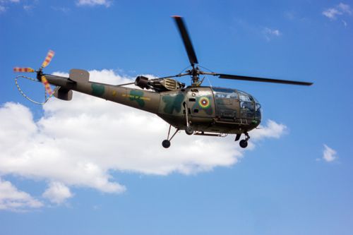 Free Military helicopter of the Zimbabwe Air Force flying against a blue sky with clouds. Stock Photo