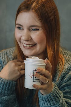 Cheerful woman enjoying a hot drink in a cozy indoor setting.