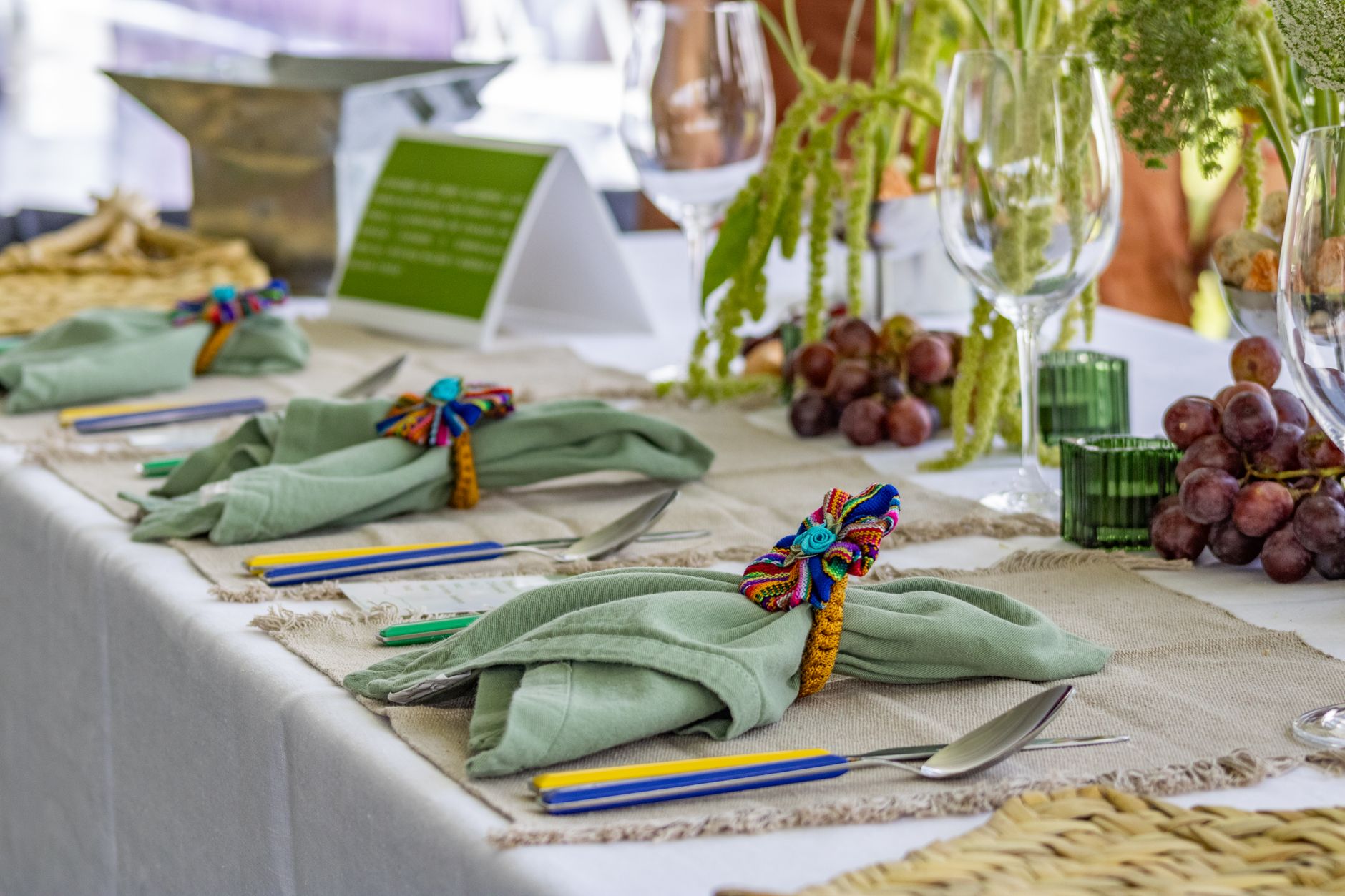 A vibrant table setting with grapes, napkins, and colorful decorations.