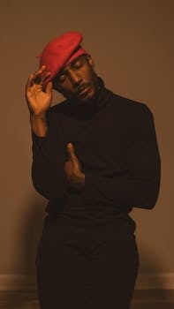 Elegant and contemplative portrait of a man wearing a red beret and black outfit, captured indoors with warm lighting.